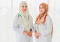 Two attractive smiling professional young adult Muslim doctors wearing cream and brown hijab standing and looking at the camera Royalty Free Stock Photo