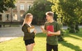 Two attractive students, female and male, having a conversation in the park near the university holding notebooks and coffee. Royalty Free Stock Photo