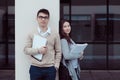 Two attractive students talking and looking in folder Outside Building at campus Royalty Free Stock Photo