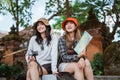 two attractive tourists sit holding a map and a camera Royalty Free Stock Photo
