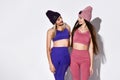 Attractive, young and fit women with long hair wearing sports clothing and knitted hats over a white background