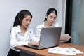 Two attractive young Asian businesswoman using laptop together in modern office. Team work business concept. Royalty Free Stock Photo