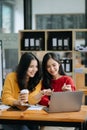 Two Attractive young Asian female college students working on the school project using laptop computer and tablet together, enjoy Royalty Free Stock Photo