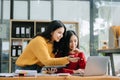 Two Attractive young Asian female college students working on the school project using laptop computer and tablet together, enjoy Royalty Free Stock Photo