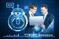Two attractive young businessmen using laptop together with glowing robot and chart hologram on blue background. Artificial