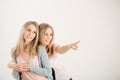 Two attrative sisters twins pointing over white background