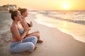 Two authentic women doing group yoga meditation on the beach at sunrise. Girls relaxing in lotus pose asana on sea shore Royalty Free Stock Photo