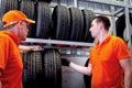 Two auto mechanic men talking during checking wheel tires at vehicle repair service shop, senior and young men working in garage, Royalty Free Stock Photo