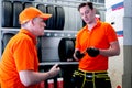 Two auto mechanic men talking during checking wheel tires at vehicle repair service shop, senior and young men working in garage, Royalty Free Stock Photo