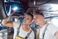 Two auto mechanics analyzing the rims of a lifted car Royalty Free Stock Photo