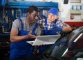 Two auto mechanics diagnosing car engine with laptop Royalty Free Stock Photo
