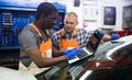 Two auto mechanics diagnosing car engine with laptop Royalty Free Stock Photo