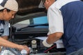 Two Auto repairman checks the engine and cooling system before traveling on a long holiday. Concept of Car care and maintenance