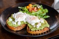 Two avocado toasts with poached eggs and fresh salad on the side, healthy delicious breakfast Royalty Free Stock Photo