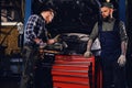 Two b mechanics working with an angle grinder in a garage. Royalty Free Stock Photo