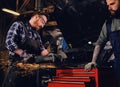 Two b mechanics working with an angle grinder in a garage. Royalty Free Stock Photo