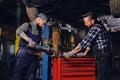 Two b mechanics working with an angle grinder in a garage. Royalty Free Stock Photo