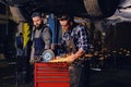 Two b mechanics working with an angle grinder in a garage. Royalty Free Stock Photo