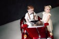 Two babies wedding - boy and girl dressed as bride and groom playing with toy car Royalty Free Stock Photo