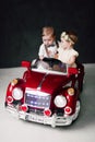 Two babies wedding - boy and girl dressed as bride and groom playing with toy car Royalty Free Stock Photo