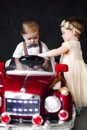 Two babies wedding - boy and girl dressed as bride and groom playing with toy car Royalty Free Stock Photo