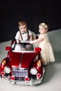 Two babies wedding - boy and girl dressed as bride and groom playing with toy car Royalty Free Stock Photo