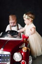 Two babies wedding - boy and girl dressed as bride and groom playing with toy car Royalty Free Stock Photo