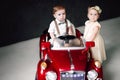 Two babies wedding - boy and girl dressed as bride and groom playing with toy car Royalty Free Stock Photo