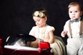 Two babies wedding - boy and girl dressed as bride and groom playing with toy car Royalty Free Stock Photo