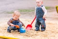 Two baby boys playing with sand in a sandbox Royalty Free Stock Photo