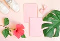 Two baby shoes, invitation envelope and green tropical monstera leaf over pink background in flatlay style with space Royalty Free Stock Photo