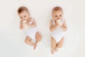 Two baby twins boy and girl with a bottle of milk on a white bed at home, baby food concept, place for text Royalty Free Stock Photo