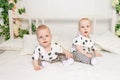 Two baby twins 8 months old sitting on the bed in the same clothes, brother-sister relationship, fashionable clothes for children Royalty Free Stock Photo