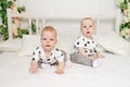 Two baby twins 8 months old sitting on the bed in the same clothes, brother-sister relationship, fashionable clothes for children Royalty Free Stock Photo