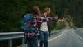 Two backpackers hitchhiking road. Couple tourists catch wait car in mountains. Royalty Free Stock Photo