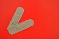 Two bactericidal plasters lie on a red background