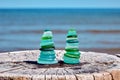 Two balanced pyramids of wet, sea-polished fragments of a blue and green glass bottle Royalty Free Stock Photo