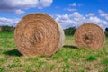 Two Circular bales of straw in a meadow under a blue sky Royalty Free Stock Photo