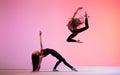 Two ballet girls with long loose hair in black tight-fitting suits dancing