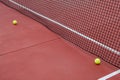 two balls next to the net of a red tennis court, racket sports concept Royalty Free Stock Photo