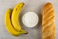 Two bananas, bowl with soft cottage cheese, loaf of bread on wooden table. Top view Royalty Free Stock Photo