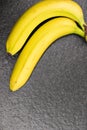 Two bananas joined together on a black plane. Exotic fruit, yellow bananas on a black stone surface. Bananas Royalty Free Stock Photo