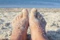 Two bare feet of caucasian woman soiled in sand with shell rock on sandy sea Royalty Free Stock Photo