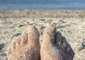 Two bare feet of caucasian woman soiled in sand with shell rock on sandy sea Royalty Free Stock Photo