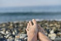 Two bare feet, slightly folded into a hug, against the sea is out of focus.