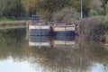 Two barges moored on a murky canal in England, filled with mud from a dredger