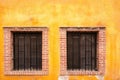 Two barred windows with colorful paed mexican background Royalty Free Stock Photo