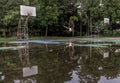 Two basketball wooden backboards with the hoop metal rings and the white net show the reflection of them on the rainwater all over Royalty Free Stock Photo