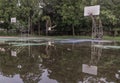 Two basketball wooden backboards with the hoop metal rings and the white net show the reflection of them on the rainwater all over Royalty Free Stock Photo