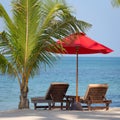 Two beach chairs, red umbrella and palm tree on the beach in Thailand Royalty Free Stock Photo